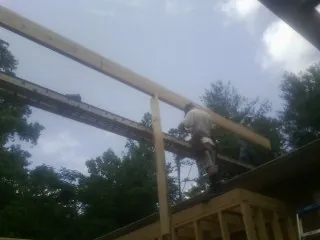 Carpenter setting a ridge beam over a new addition frame — Ice Dam Removal by Roofing Brothers in Elm Mott