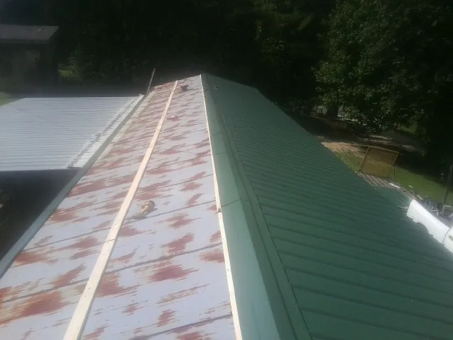 Old rusted panels beside newly installed green metal roofing — Wind Damage Roof Repair by Roofing Brothers in Elm Mott
