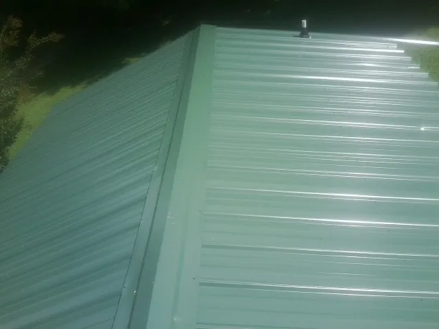 New green metal panels meeting at the ridge of a roof — Flat Roof Repair work by our crew in Elm Mott