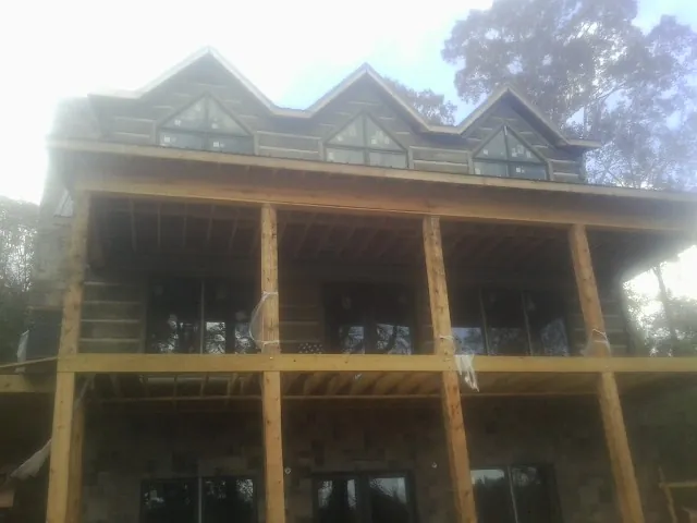 Dormers and porch framing on a large log home under construction — Roof Coating work by our crew in Elm Mott