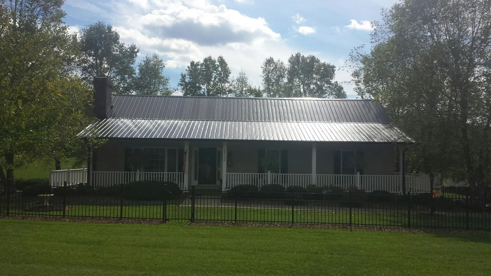 Gray metal roof on a brick ranch with a full width front porch — Gutter Guard Installation work by our crew in Elm Mott