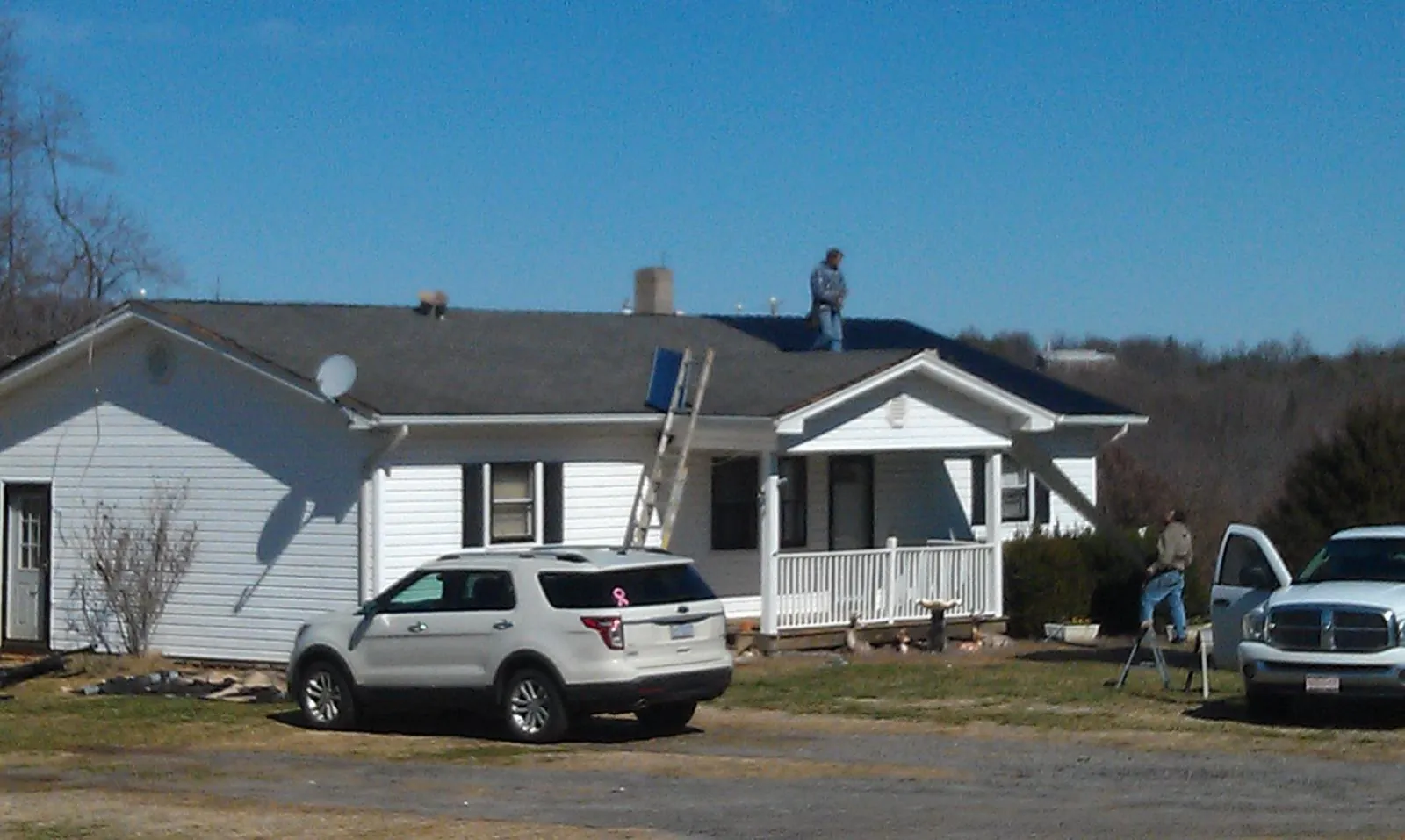 Roofers stripping shingles from a white ranch house roof in Elm Mott