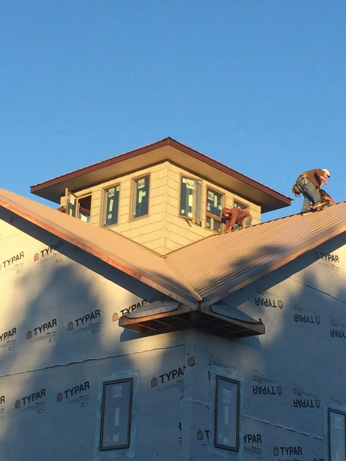 Roofers working around a rooftop cupola on a new metal roof at sunset — Roof Waterproofing in Elm Mott by Roofing Brothers